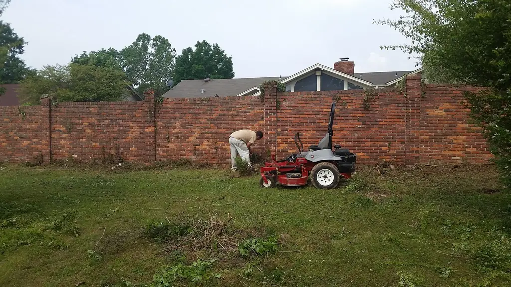 A zero turn mower being used along a brick boundary wall